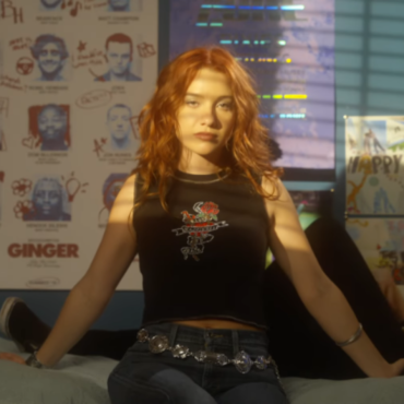 Linsey Urrea sentada em uma cada de um cenário de um quarto encarando a cãmera