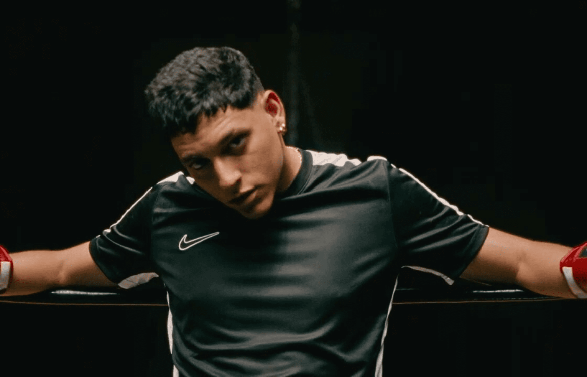 La Cruz sentado em um ring de luta encarando a câmera enquanto veste uma camisa esportiva da nike.