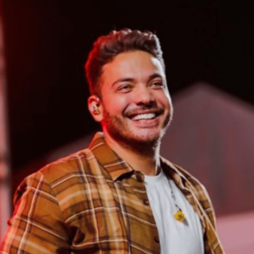 Wesley Safadão sorri para o público em cima de um palco.