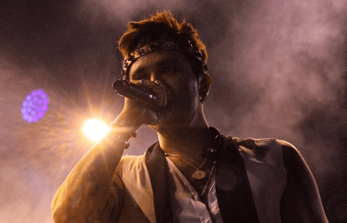 Luan Santana canta com microfone de olhos fechados para o público.