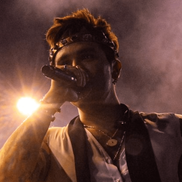 Luan Santana canta com microfone de olhos fechados para o público.