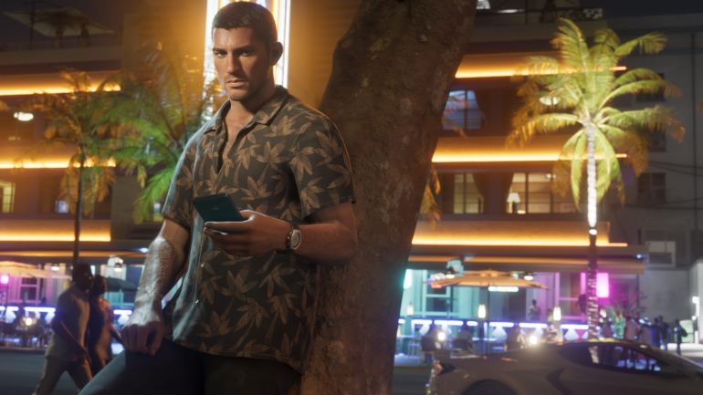 Personagem masculino de GTA 6 encostado em uma árvore no coração vibrante de Vice City, à noite, com expressão séria e celular na mão, em meio ao clima tropical e luzes neon da cidade.