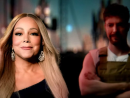 Mariah Carey em destaque, usando vestido preto de um ombro só e brincos brilhantes, com MrBeast desfocado ao fundo, vestindo colete marrom e camiseta branca, em cena do videoclipe Type Dangerous.