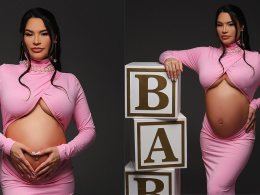 aissa Barbosa grávida posa para ensaio fotográfico usando vestido rosa justo com recorte na barriga. Em uma das fotos, ela forma um coração com as mãos sobre o ventre; na outra, apoia a mão em blocos decorativos que formam a palavra "BABY". O cenário tem fundo preto e iluminação suave, destacando a silhueta da gestante.