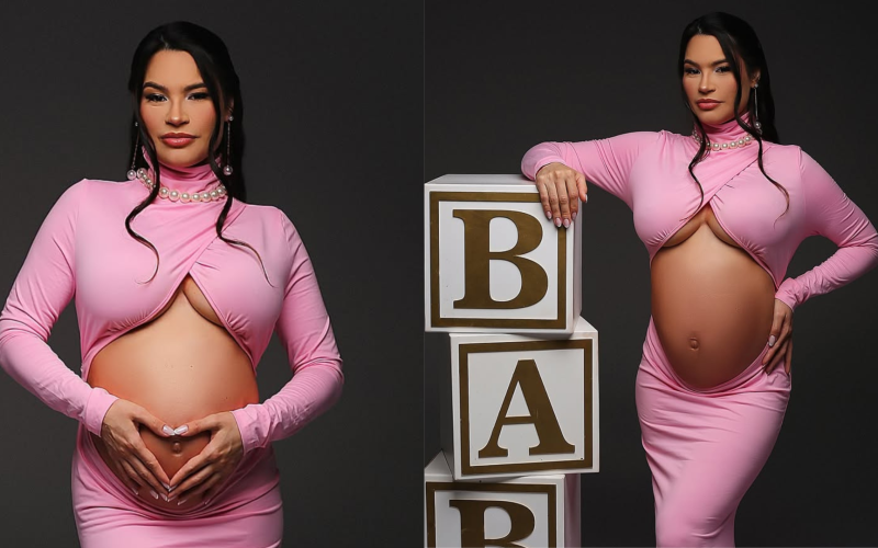 aissa Barbosa grávida posa para ensaio fotográfico usando vestido rosa justo com recorte na barriga. Em uma das fotos, ela forma um coração com as mãos sobre o ventre; na outra, apoia a mão em blocos decorativos que formam a palavra "BABY". O cenário tem fundo preto e iluminação suave, destacando a silhueta da gestante.